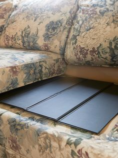 a close up of a flowered couch with a black mat on the bottom half