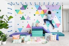 a room with colorful geometric wallpaper and pillows on the floor, along with potted plants