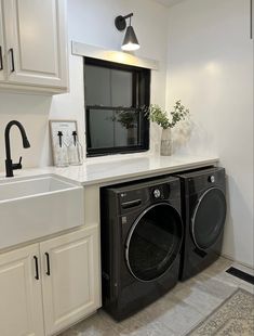 a washer and dryer in a small room with white cabinets on the wall