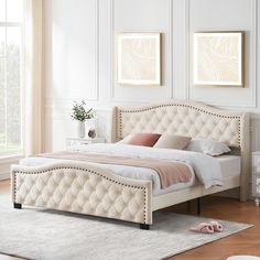 a white bed sitting in a bedroom on top of a hard wood floor next to a window