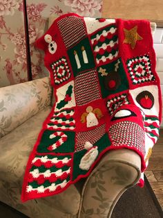 a red and green christmas afghan sitting on top of a couch next to a white chair