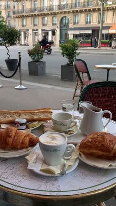 a table with coffee and croissants on it in front of a building