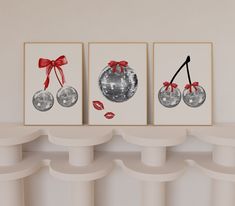 three art prints with red bows are hanging on the wall next to white pedestals