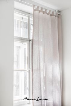 a white curtain hanging in front of a window with the words aman linen on it