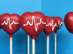 red heart shaped lollipops with white writing on them are lined up against a blue background