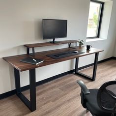 a computer desk with a monitor and keyboard on it in an empty room next to a window