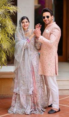 a man and woman standing next to each other in front of a building with palm trees