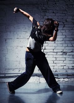 black and white photograph of a man dancing in front of a brick wall