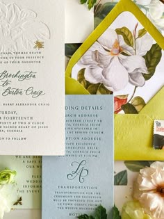 the wedding stationery is laid out on top of each other with flowers and foliage