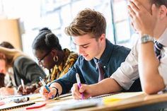 three people sitting at a table with pens and notebooks in front of them,