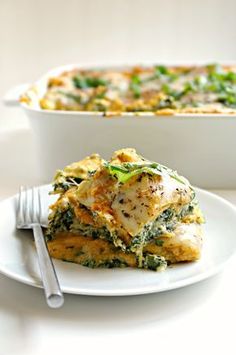 a white plate topped with lasagna covered in cheese and spinach next to a casserole dish