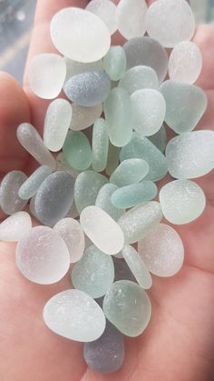 small white and gray sea glass pieces being held in someone's hand