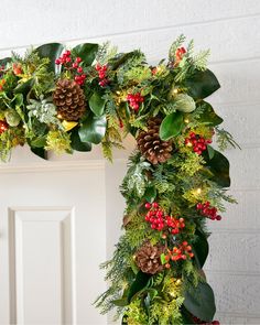 a christmas wreath with pine cones, holly and red berries on the front door frame