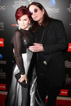 two people standing next to each other on a red carpet with one person wearing a black suit