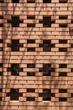 a building made out of bricks with trees in the foreground and shadows on the wall