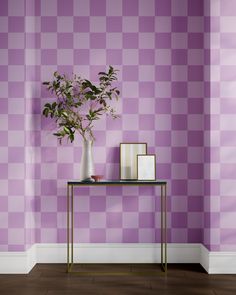 a vase with flowers on a table in front of a purple checkerboard wall