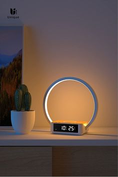 a clock sitting on top of a table next to a potted cactus