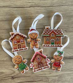 christmas ornaments made out of cross stitch fabric on wooden table with white ribbon and gingerbread house ornament