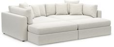 a large white couch with lots of pillows on it's back and arms, sitting in front of a white background