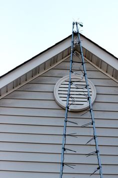 a ladder is attached to the side of a house that has a round window on it