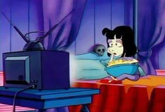 a cartoon character laying in bed next to a tv and a skull on the table