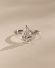 a pear shaped diamond ring on a white surface