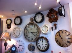 many clocks are hanging on the wall with lights