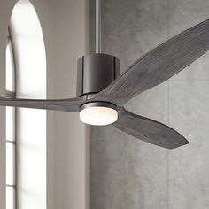 a ceiling fan that is hanging from the ceiling in a room with grey walls and flooring