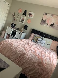 a bedroom with pink bedding and pictures on the wall