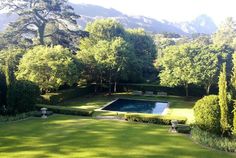 an outdoor pool surrounded by trees and bushes in the middle of a lush green yard