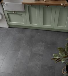 a kitchen with green cabinets and gray flooring in the center is a white sink