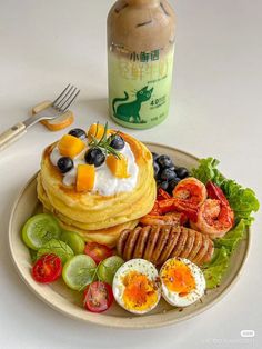 a plate topped with pancakes, fruit and vegetables next to a bottle of ketchup