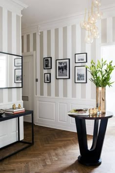 a living room filled with furniture and pictures on the wall next to a table in front of a mirror