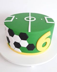 a green and white cake with soccer balls on the top is sitting on a plate