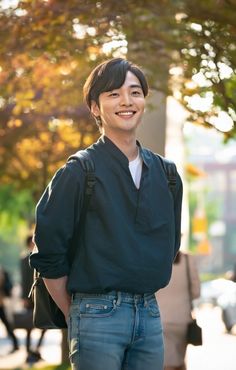 a young man standing in the street with his back to the camera and smiling at the camera