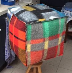 a multicolored blanket sitting on top of a wooden stand next to a sink