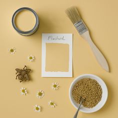 a yellow background with flowers, a paintbrush, and a photo frame next to it