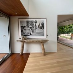 a wooden table sitting in the middle of a living room next to a large window