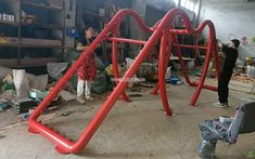 two people are working on a red bike frame