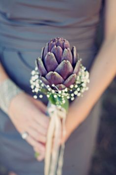 a bridesmaid holding a bouquet of flowers in her hands and wearing a gray dress