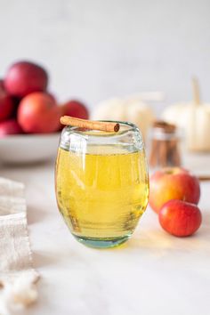 a glass jar filled with liquid sitting on top of a table next to some apples