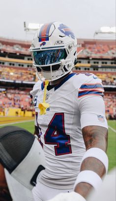 a football player is holding his helmet on the field