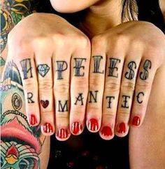 a woman with tattoos on her hands holding up two fingers that say happiness and romantic