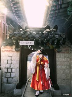 a woman dressed in traditional chinese clothing is standing under an archway