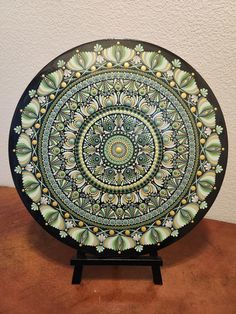 a decorative plate is sitting on a wooden table with a white wall in the background