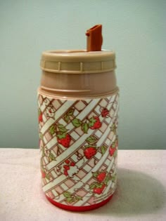 a coffee cup with strawberries on it is sitting on a table next to a wall