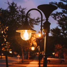 an old fashioned street lamp lit up in the evening with its light shining on it