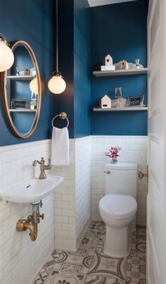 a white toilet sitting next to a sink in a bathroom under a mirror and lights