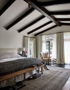 a large bed sitting in the middle of a bedroom next to two chairs and a window