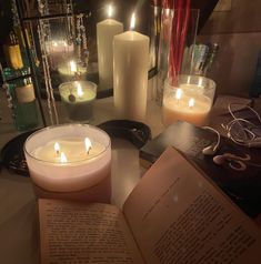 an open book sitting on top of a table next to candles